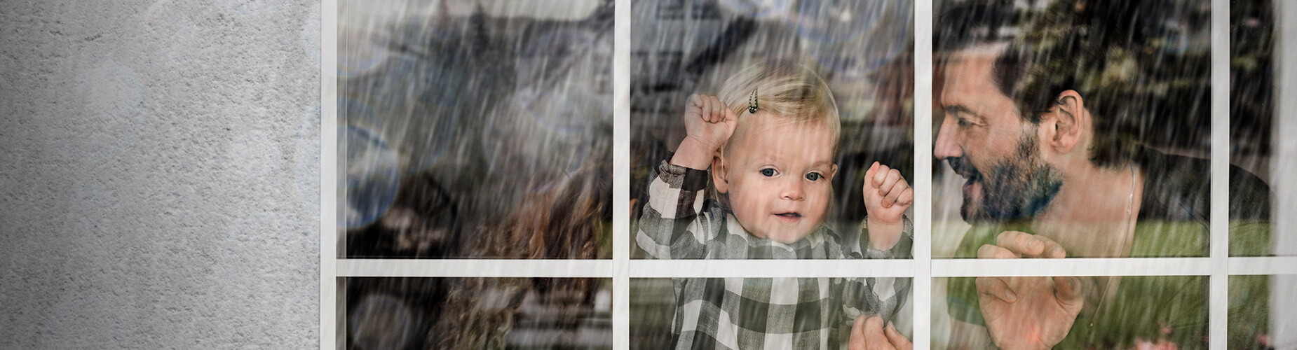 Wohngebäudeversicherung -  Mann mit Kind am Fenster 